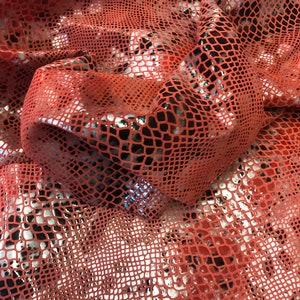 May include: Red and silver snakeskin fabric with a textured pattern. The fabric is shiny and has a metallic sheen.