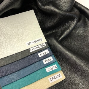 May include: A close-up of six leather swatches in various colors, including off-white, charcoal, navy, teal, aqua, and cream. The swatches are arranged in a stack, with the off-white swatch on top and the cream swatch on the bottom. The swatches are labeled with their respective colors.