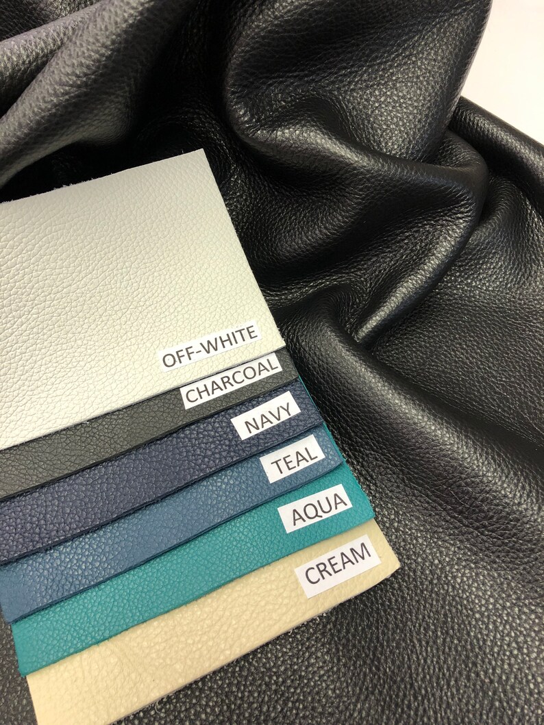 May include: A close-up of six leather swatches in various colors, including off-white, charcoal, navy, teal, aqua, and cream. The swatches are arranged in a stack, with the off-white swatch on top and the cream swatch on the bottom. The swatches are labeled with their respective colors.