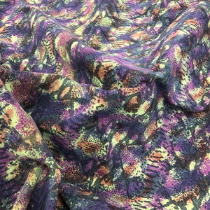 May include: Purple, green, and brown fabric with a snake skin pattern.