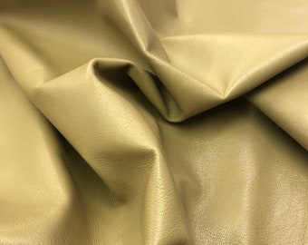 May include: A close-up of a piece of soft, light brown leather. The leather has a smooth, slightly textured surface.