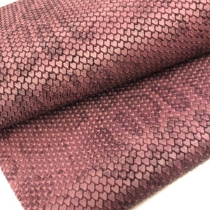 May include: A close-up of a textured fabric with a raised pattern of small hearts. The fabric is a deep burgundy color.