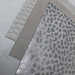 May include: Three different types of white faux leather with embossed patterns. The first is a smooth, textured leather with a subtle pattern. The second is a smooth, textured leather with a more pronounced pattern. The third is a smooth, textured leather with a large, bold pattern.