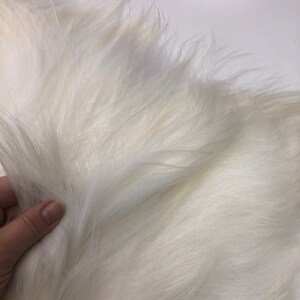 Puede incluir: Primer plano de una tela de piel blanca y esponjosa. La piel es suave y mullida, con un ligero brillo.