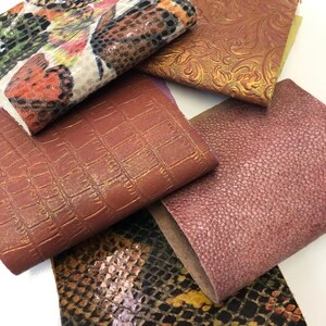 May include: Five different fabric swatches with various textures and patterns. The swatches include a floral pattern, a crocodile embossed pattern, a snakeskin pattern, a pink textured pattern, and a gold embossed floral pattern.