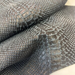 Puede incluir: Primer plano de una piel de serpiente azul oscuro con un patr&oacute;n texturizado y escamoso.