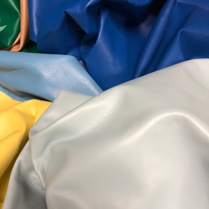 May include: A collection of leather swatches in various colors, including blue, light blue, yellow, and green. The leather is smooth and textured, with a soft, supple feel.