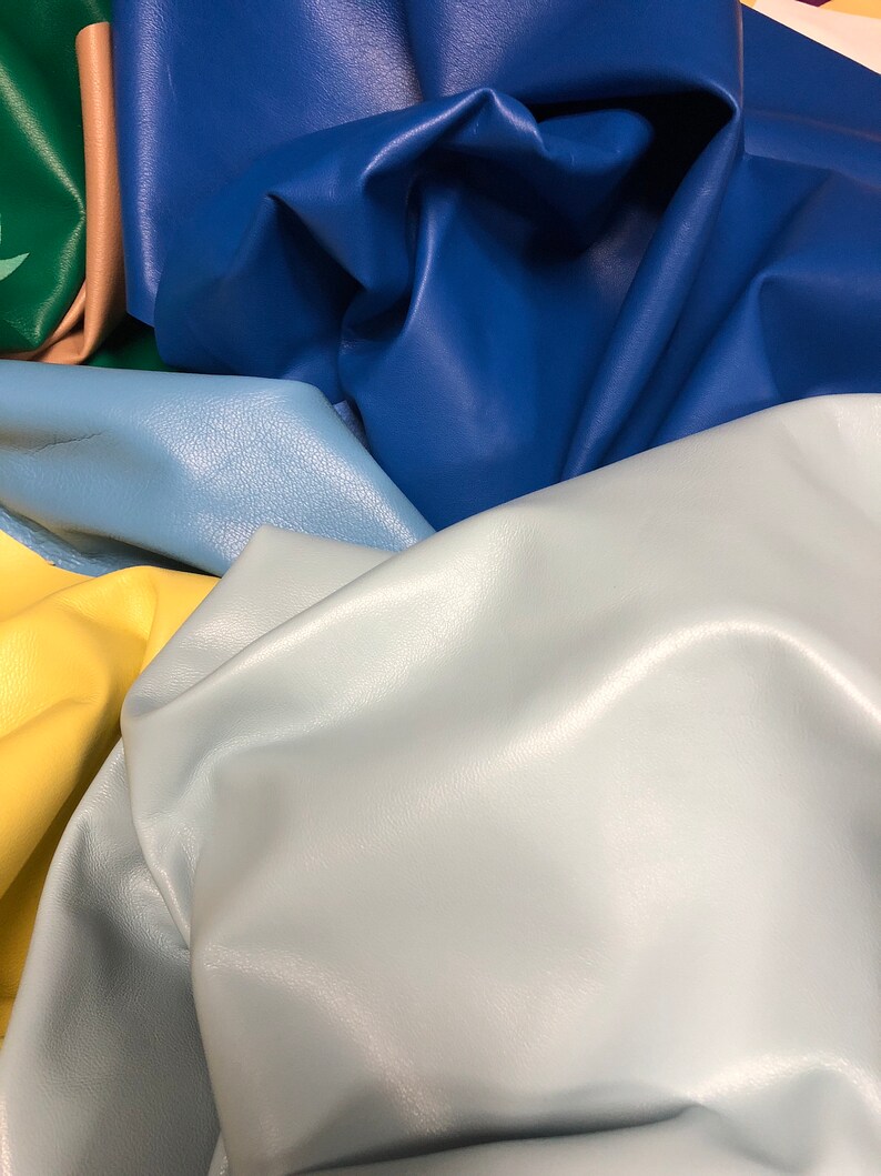 May include: A collection of leather swatches in various colors, including blue, light blue, yellow, and green. The leather is smooth and textured, with a soft, supple feel.