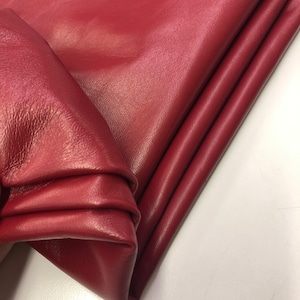May include: A close-up of a folded piece of burgundy leather. The leather has a smooth, textured surface.