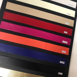 May include: A sample card of ten different colors of leather, including off-white, cream, nude, red, fuchsia, coral, purple, black, and gold metallic.