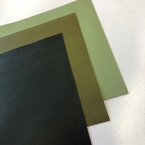 May include: Three sheets of faux leather in different shades of green. The top sheet is a light green, the middle sheet is a darker green, and the bottom sheet is black.