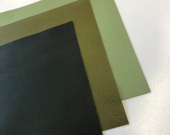 May include: Three sheets of faux leather in different shades of green. The top sheet is a light green, the middle sheet is a darker green, and the bottom sheet is black.