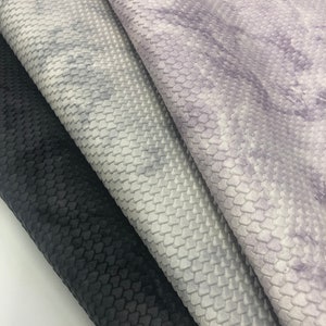May include: Three fabric swatches with a textured, honeycomb-like pattern. The swatches are in black, white with a light purple marbling, and a solid light purple.