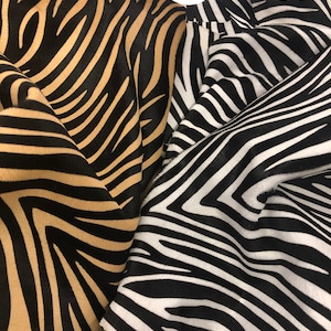 May include: Two pieces of fabric with a zebra print pattern. One piece is black and white, and the other is black and tan.