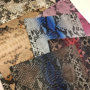K&ouml;nnte beinhalten: Eine Sammlung von Kunstleder im Schlangenhaut-Look in verschiedenen Farben und Mustern, darunter Schwarz, Wei&szlig;, Braun, Blau, Rosa und Rot.