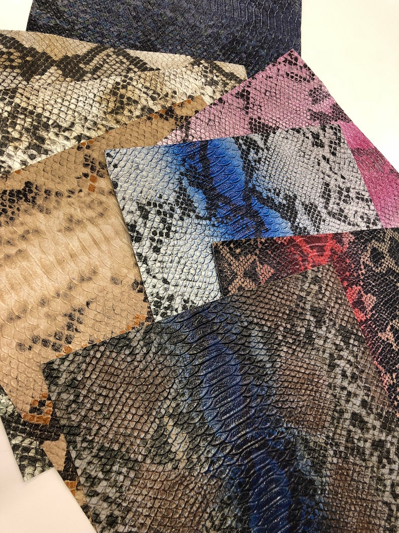 K&ouml;nnte beinhalten: Eine Sammlung von Kunstleder im Schlangenhaut-Look in verschiedenen Farben und Mustern, darunter Schwarz, Wei&szlig;, Braun, Blau, Rosa und Rot.