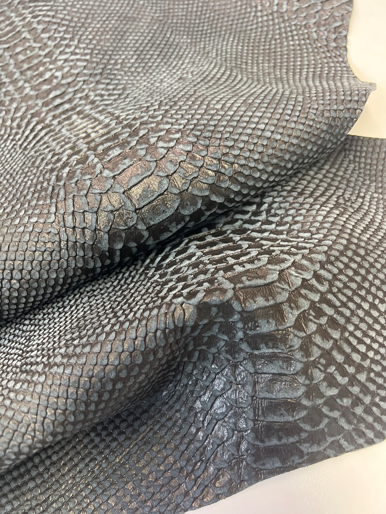 Puede incluir: Primer plano de una piel de serpiente azul oscuro con un patr&oacute;n texturizado y escamoso.