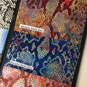 May include: Close-up of three swatches of iridescent faux leather with a textured snake skin pattern. The swatches are labeled "Metallic Multi Red", "Metallic Multi Blue", and "Metallic Multi Green".