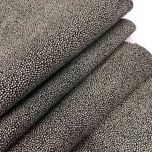 May include: Close-up of black fabric with a white polka dot pattern. The fabric is folded in layers, showing the texture and detail of the pattern.