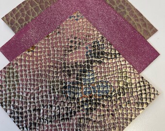 May include: Three pieces of faux leather in different textures and colors. The bottom piece is a snakeskin pattern with a metallic sheen. The middle piece is a solid pink with glitter. The top piece is a brown with a crocodile pattern.