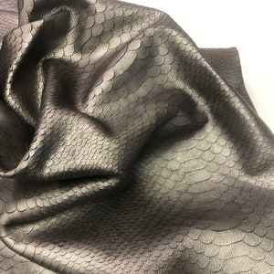 May include: A close-up of a piece of dark gray snakeskin leather with a textured surface.