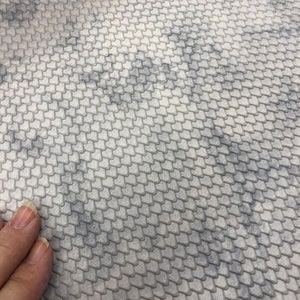 May include: Close-up of a textured surface with a repeating pattern of small, overlapping scales in shades of gray. The pattern creates a subtle, three-dimensional effect. The surface has a marbled appearance.