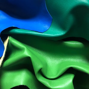 May include: Close-up of a stack of leather in various colors, including blue, green, and purple. The leather is soft and supple, with a natural grain.