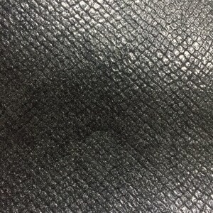 May include: Close-up of a black textured fabric with a subtle sheen. The fabric has a repeating pattern of small, raised squares.