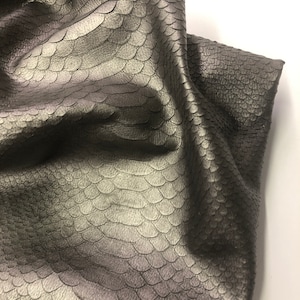 May include: A close-up of a piece of gray leather with a textured, scaly pattern.