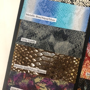 May include: Close-up of fabric swatches in various colors and patterns, including light beige with black spots, metallic blue with aqua and silver accents, grey suede, metallic gold with silver and bronze accents, and ochre with purple, pink, and orange accents.