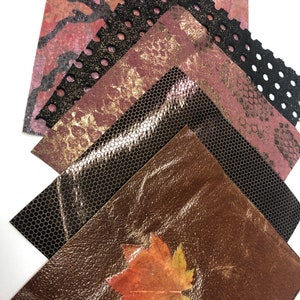 May include: A stack of four different textured paper sheets in shades of brown, pink, and black. The top sheet has a coral design, the second sheet has a gold glitter finish, the third sheet has a black mesh pattern, and the bottom sheet has a brown leather-like texture with a pressed leaf.