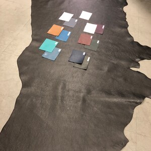 May include: A large piece of black leather with several small leather swatches in various colors, including teal, brown, gray, and dark green.