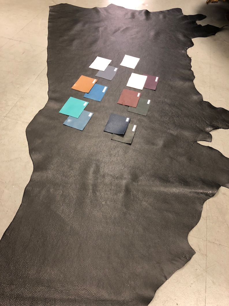 May include: A large piece of black leather with several small leather swatches in various colors, including teal, brown, gray, and dark green.