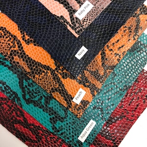 May include: Close-up of six different colors of faux snakeskin fabric swatches. The colors are: Baby Pink, Navy, Peach, Aqua Green, Wine Red, and Black.