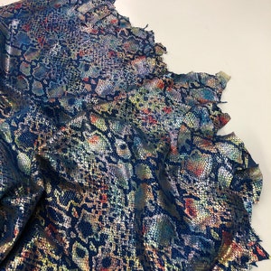 May include: A piece of iridescent blue fabric with a snakeskin pattern. The fabric has a metallic sheen and is folded in a way that shows the texture of the material.