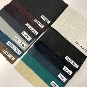 May include: A collection of 14 leather swatches in various colors, including off-white, forest, merlot, charcoal, eggplant, smoke, dove grey, ocean blue, natural, navy, teal, aqua, and cream.