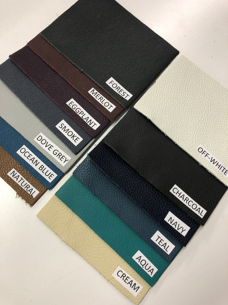 May include: A collection of 14 leather swatches in various colors, including off-white, forest, merlot, charcoal, eggplant, smoke, dove grey, ocean blue, natural, navy, teal, aqua, and cream.