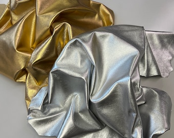 May include: Two pieces of fabric, one gold and one silver, are crumpled together. The fabric has a metallic sheen.