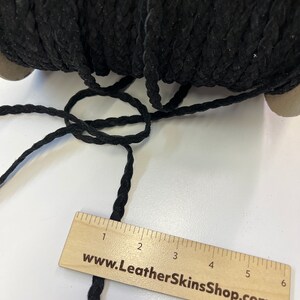May include: Black braided leather cord, approximately 3 inches long, with a wooden ruler showing the measurement. The ruler has the website www.LeatherSkinsShop.com printed on it.
