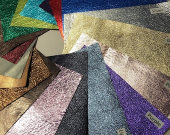 May include: A collection of textured, metallic-look leather swatches in various colors, including emerald green, turquoise, lipstick red, and royal blue. Each swatch has a label with its color name. The swatches are arranged in a fan shape.