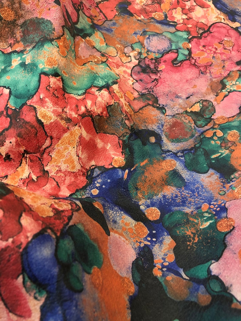 May include: Abstract fabric with a colorful, swirling pattern in shades of pink, blue, green, and orange. The fabric has a textured, almost metallic look.