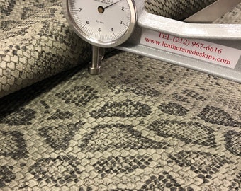 May include: Close-up of a gray snakeskin leather with a gauge measuring the thickness of the material. The gauge reads 0.1 mm and the text on the gauge reads "CALATI MADE IN ITALY". The text "TEL (212) 967-6616 www.leathersuedeskins.com" is also visible.