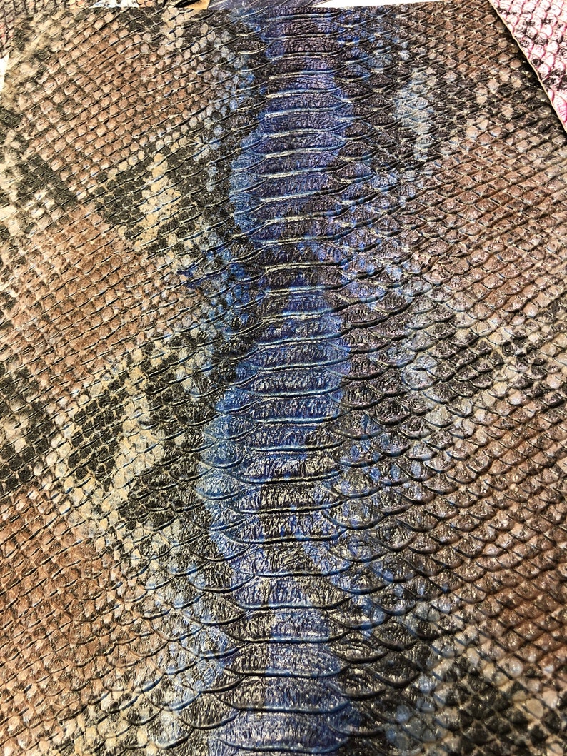 K&ouml;nnte beinhalten: Nahaufnahme eines Schlangenlederstoffs mit einem braunen und schwarzen Muster auf der linken Seite und einem blauen und schwarzen Muster auf der rechten Seite.