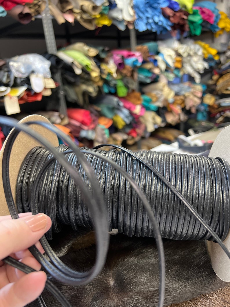 May include: A spool of black leather cord, wound tightly and ready for crafting projects. The cord is smooth and supple, perfect for making jewelry, belts, or other leather goods.