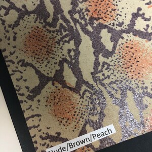 May include: Close-up of a snakeskin-patterned fabric in shades of brown, peach, and silver. The fabric has a label that reads "Nude/Brown/Peach".