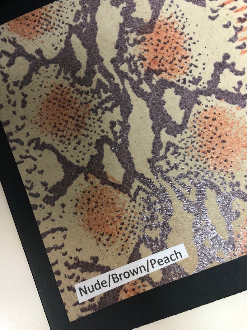 May include: Close-up of a snakeskin-patterned fabric in shades of brown, peach, and silver. The fabric has a label that reads "Nude/Brown/Peach".