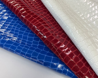 May include: Three pieces of fabric with a crocodile skin pattern. The fabric is white, red, and blue.