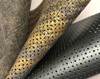 May include: Three pieces of fabric with different textures and colors. One is a dark brown fabric with a subtle pattern. Another is a black fabric with small holes. The third is a gold fabric with a pattern of small holes.