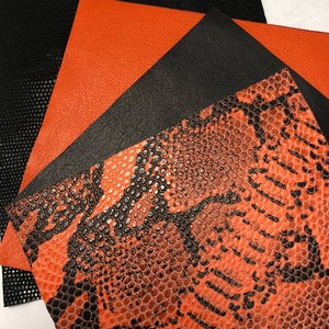 May include: An assortment of leather and faux leather fabric swatches in various textures and colors. The swatches include black perforated, orange, black, and orange snake print patterns. The fabrics are arranged in an overlapping fan shape.