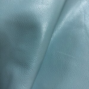May include: A close-up of a piece of light blue leather with a textured surface.